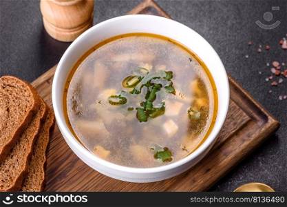 Delicious healthy soup with sorrel, tomato, potatoes, spices and herbs in a white bowl against a dark concrete background. Vegetarian dish. Delicious healthy soup with sorrel, tomato, potatoes, spices and herbs in a white bowl