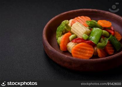 Delicious healthy vegetables steamed carrots, broccoli, asparagus beans and peppers on a dark concrete background