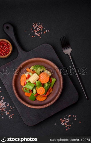 Delicious healthy vegetables steamed carrots, broccoli, asparagus beans and peppers on a dark concrete background