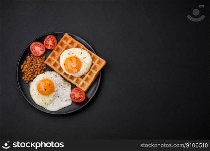 Delicious hearty breakfast consisting of a fried egg, Belgian waffle, lentils, microgreens with spices and herbs on a dark concrete background