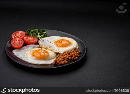 Delicious hearty breakfast consisting of two fried eggs, canned lentils, microgreens with spices and herbs on a dark concrete background