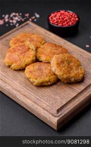 Delicious hearty vegetarian or vegan dish in the form of cutlets or patties consisting of potatoes, carrots, onions and beans on a dark concrete background