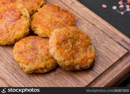 Delicious hearty vegetarian or vegan dish in the form of cutlets or patties consisting of potatoes, carrots, onions and beans on a dark concrete background