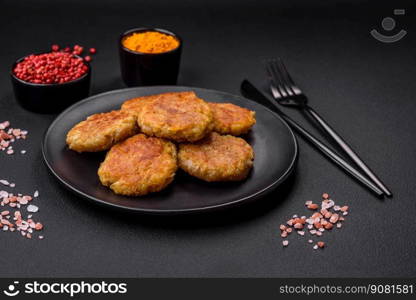 Delicious hearty vegetarian or vegan dish in the form of cutlets or patties consisting of potatoes, carrots, onions and beans on a dark concrete background