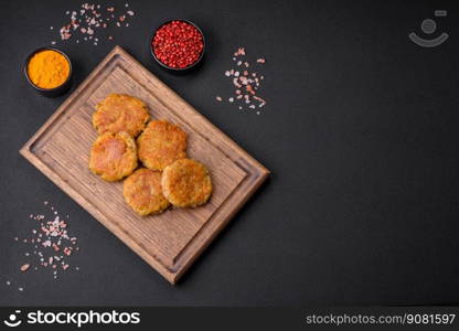 Delicious hearty vegetarian or vegan dish in the form of cutlets or patties consisting of potatoes, carrots, onions and beans on a dark concrete background