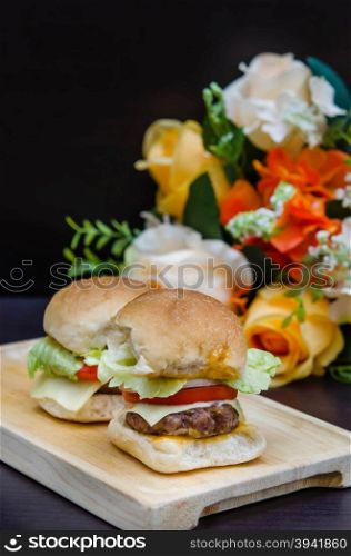 Delicious homemade gourmet cheese burgers made from beef with fresh ingredients placed on wooden platters. gourmet cheese burgers