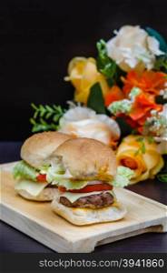 Delicious homemade gourmet cheese burgers made from beef with fresh ingredients placed on wooden platters. gourmet cheese burgers