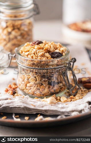 Delicious homemade granola in glass jar on gray background. Breakfast. Healthy food sweet dessert snack. Diet nutrition concept. Vegetarian food.. Delicious homemade granola