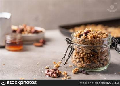 Delicious homemade granola in glass jar on gray background. Breakfast. Healthy food sweet dessert snack. Diet nutrition concept. Vegetarian food.. Delicious homemade granola