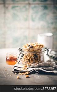 Delicious homemade granola in glass jar on gray background. Breakfast. Healthy food sweet dessert snack. Diet nutrition concept. Vegetarian food.. Delicious homemade granola
