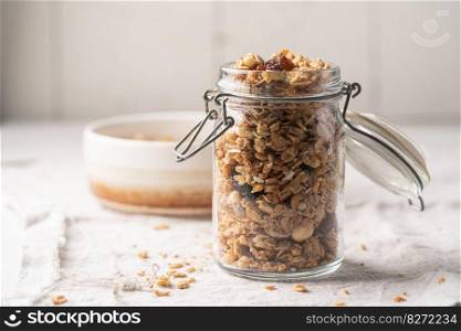 Delicious homemade granola in glass jar on white background. Breakfast. Healthy food sweet dessert snack. Diet nutrition concept. Vegetarian food.. Delicious homemade granola