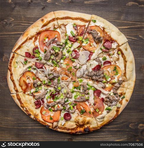 delicious homemade pizza with tomatoes, sausage, onion, chicken and cheese on wooden rustic background top view close up