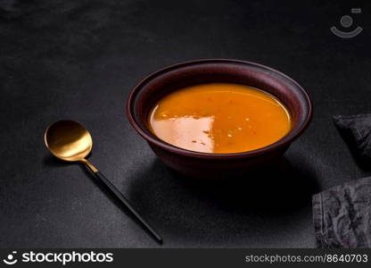 Delicious hot pumpkin and carrot soup puree with spices and herbs. Vegetarian cuisine. Delicious hot pumpkin and carrot soup puree with spices and herbs