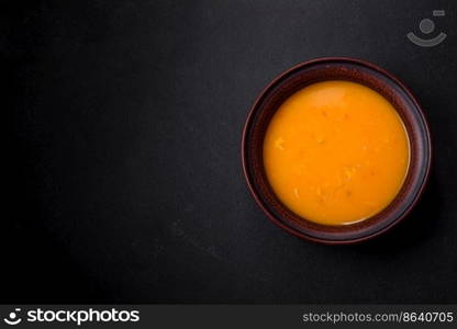 Delicious hot pumpkin and carrot soup puree with spices and herbs. Vegetarian cuisine. Delicious hot pumpkin and carrot soup puree with spices and herbs