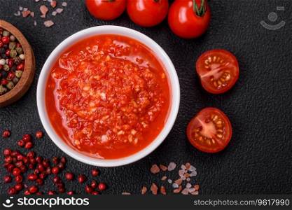Delicious hot sπcy red sauce with sa<and sπces in a ceramic bowl on a dark concrete background