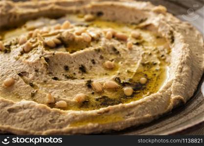 Delicious hummus with pine nuts and olive oil. Close-up.