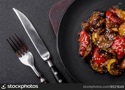 Delicious juicy fresh salad of baked eggplant, tomatoes, sweet peppers, sesame seeds, spices and salt on a dark concrete background