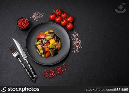 Delicious juicy fresh salad of baked eggplant, tomatoes, zucchini, onions, spices and salt on a dark concrete background