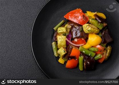 Delicious juicy fresh salad of baked eggplant, tomatoes, zucchini, onions, spices and salt on a dark concrete background