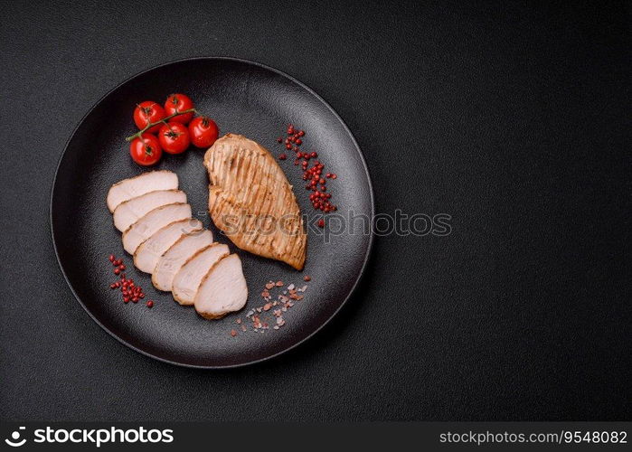 Delicious juicy grilled chicken fillet with salt, spices and herbs on a dark concrete background