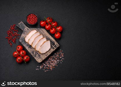 Delicious juicy grilled chicken fillet with salt, spices and herbs on a dark concrete background