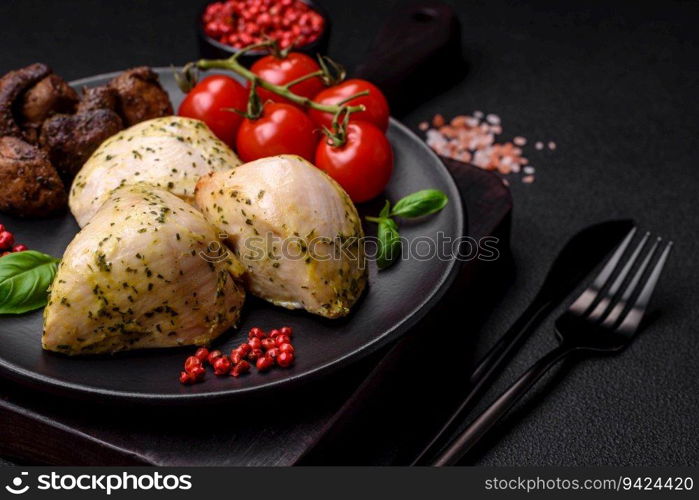 Delicious juicy grilled chicken with salt, spices and herbs with vegetables on a dark concrete background