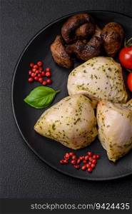 Delicious juicy grilled chicken with salt, spices and herbs with vegetables on a dark concrete background