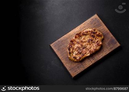 Delicious juicy grilled pork steak with spices and herbs on a wooden cutting board