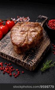 Delicious juicy pork or beef steak cooked on the grill with salt and spices on a textured concrete background