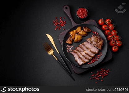 Delicious juicy pork or beef steak grilled with salt, spices and herbs on a textured concrete background