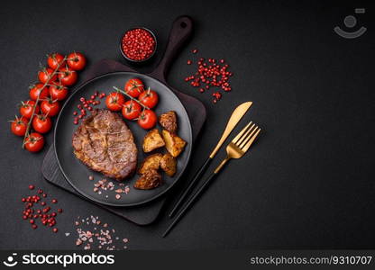 Delicious juicy pork or beef steak grilled with salt, spices and herbs on a textured concrete background