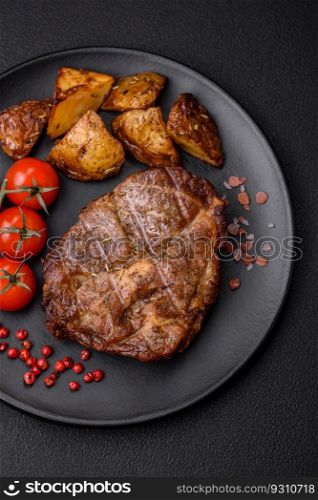 Delicious juicy pork or beef steak grilled with salt, spices and herbs on a textured concrete background