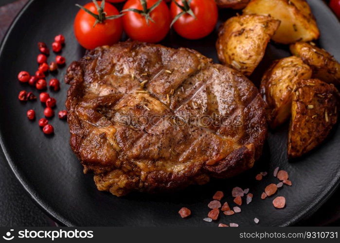 Delicious juicy pork or beef steak grilled with salt, spices and herbs on a textured concrete background