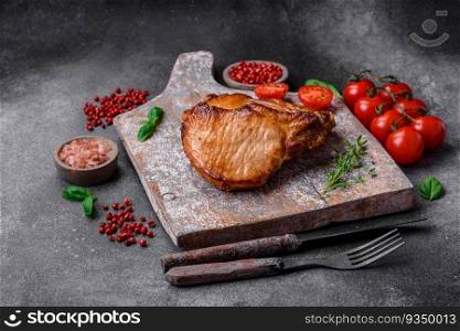 Delicious juicy pork or beef steak with salt, spices and herbs on a textured concrete background