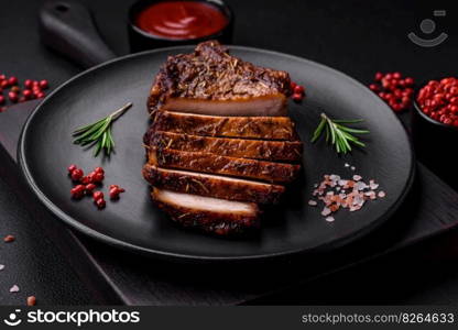 Delicious juicy pork steak on the bone with spices and herbs cut into slices on a dark concrete background