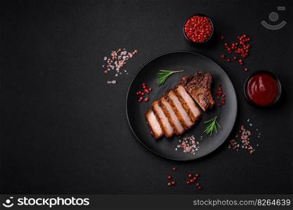 Delicious juicy pork steak on the bone with spices and herbs cut into slices on a dark concrete background