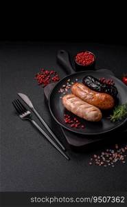 Delicious juicy sausages of several varieties grilled with salt, spices and herbs on a dark concrete background