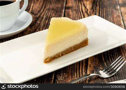 Delicious lemon cheesecake served with coffee on wooden table