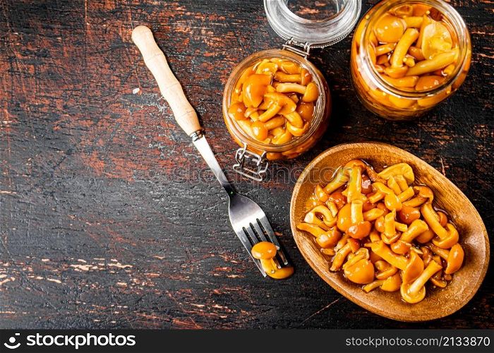 Delicious marinated mushrooms in a jar and on a plate. Against a dark background. High quality photo. Delicious marinated mushrooms in a jar and on a plate.