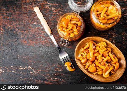 Delicious marinated mushrooms in a jar and on a plate. Against a dark background. High quality photo. Delicious marinated mushrooms in a jar and on a plate.