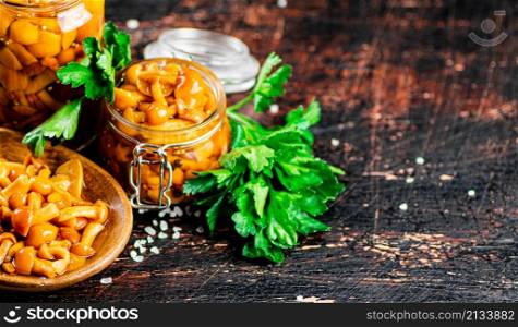 Delicious marinated mushrooms in a jar and on a plate. Against a dark background. High quality photo. Delicious marinated mushrooms in a jar and on a plate.