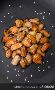 Delicious marinated mussels with spices and herbs on a ceramic plate on a dark concrete background