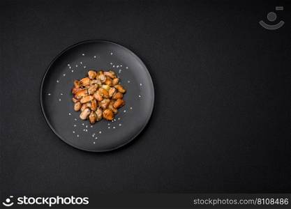 Delicious marinated mussels with spices and herbs on a ceramic plate on a dark concrete background