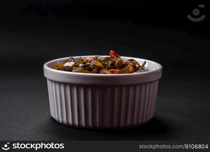 Delicious marinated seaweed with paprika, spices and salt on a dark concrete background. Delicious vegetarian salad