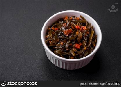 Delicious marinated seaweed with paprika, spices and salt on a dark concrete background. Delicious vegetarian salad