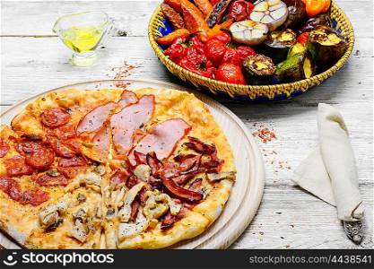 Delicious meat pizza. Pizza with meat and bacon and dish of roasted vegetables