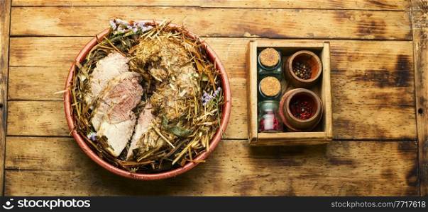 Delicious meat roasted in fresh hay. Baked pork meat in spicy herbs.. Roast pork in hay with herbs,top view