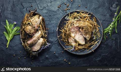Delicious meat roasted in fresh hay. Baked pork meat in spicy herbs.Autumn food. Roast pork in hay with herbs