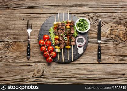 delicious meat skewer black slate with fork butter knife wooden table. Resolution and high quality beautiful photo. delicious meat skewer black slate with fork butter knife wooden table. High quality beautiful photo concept