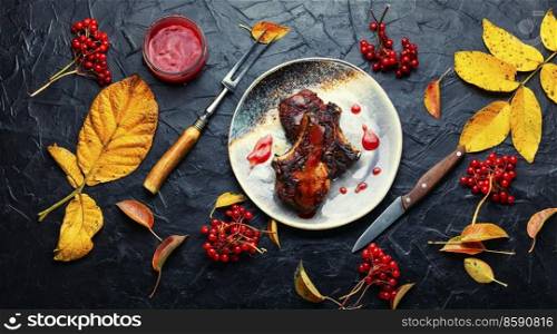 Delicious meat steak with autumn berry sauce on slate background. Fried pork with viburnum.